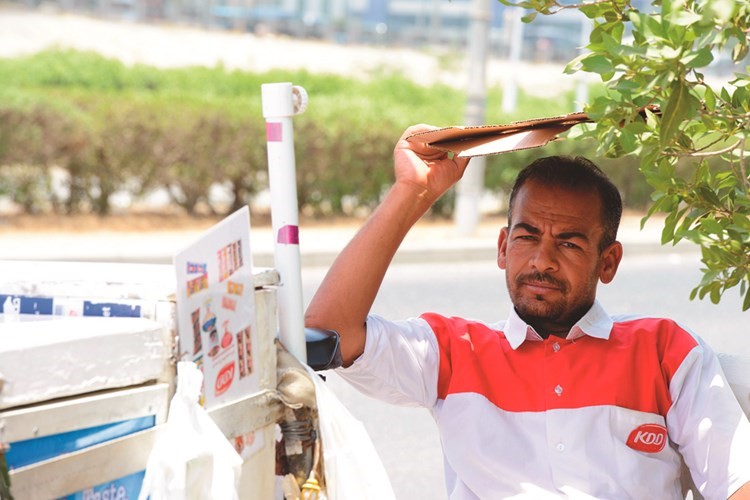 بائع الآيس كريم يختبأ من أشعة الشمس في ظل موجة الحر﻿