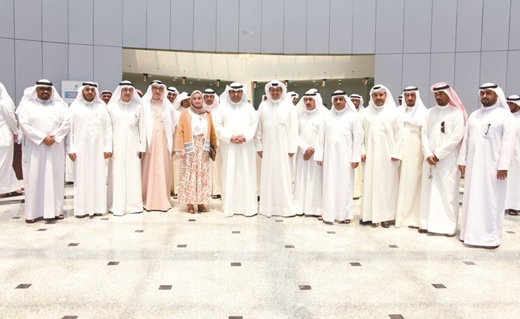 الوزير خالد الروضان وم.خلود الشهاب وعدد من قياديي وزارة المواصلات وممثل أهالي مدينة صباح الأحمد والحضور في صورة جماعية أمام مقسم مدينة صباح الأحمد السكنية (زين علام)﻿