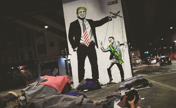مشردون ينامون تحت غرافيتي تصور ترامب يتلاعب بـالدمية رئيس البرازيل جايير بولسونارو في ساو باولو(رويترز) ﻿
