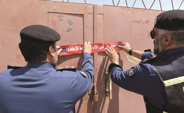 رجالا إطفاء خلال وضعهما لعلامة الغلق الإداري على احد المخازن المخالفة﻿