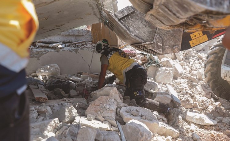 عناصر الخوذ البيضاء يبحثون عن ناجين تحت انقاض مبان دمرتها غارات في قرية دير شرقي	(أ.ف.ب)﻿