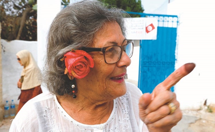 مسنة تونسية ترفع اصبعها المدموغ بالحبر بعد الإدلاء بصوتهافي العاصمة ﻿