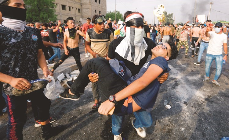 عراقي يحمل جريحا اصيب في تصدي قوات الامن للمتظاهرين في بغداد أمس	(رويترز)﻿