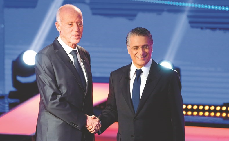 المرشحان الرئاسيان التونسيان نبيل قروي وقيس سعيد يتصافحان قبل المناظرة التلفزيونية	(رويترز)﻿