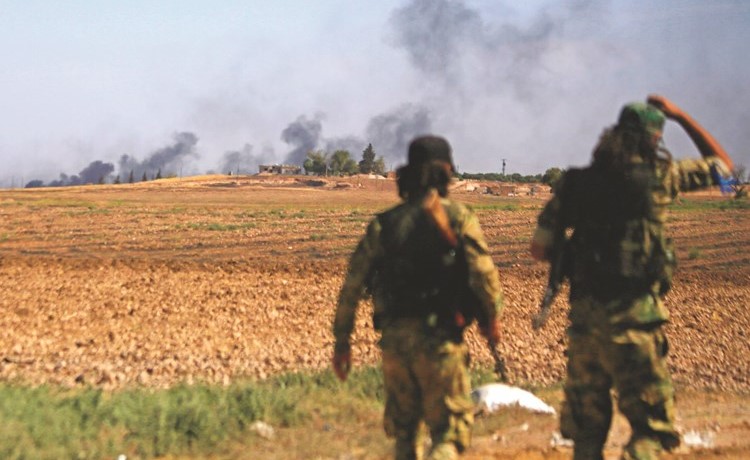مقاتلان من المعارضة السورية المدعومة من تركيا يراقبان الدخان المتصاعد من بلدة تل ابيض خلال معارك امس 	(ا.ف.پ) ﻿