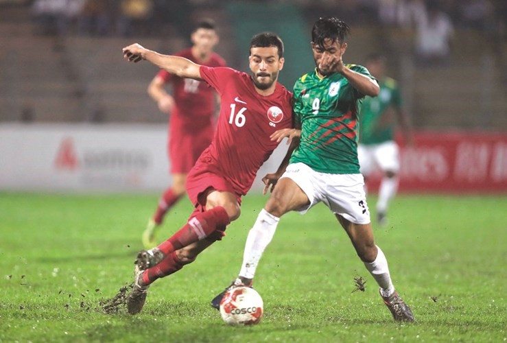 مدافع قطر بوعلام في صراعه على الكرة أمام لاعب بنجلاديش﻿