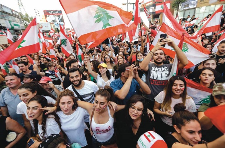  متظاهرون لبنانيون يلوحون بأعلام وطنية على طريق سريع يربط بيروت بشمال لبنان في زوق مكايل          (أ.ف.پ)