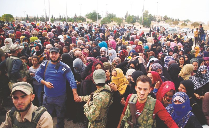 نازحون سوريون ينتظرون لتلقي المساعدات من الهلال الاحمر التركي في تل ابيض أمس	(أ.ف.پ)﻿
