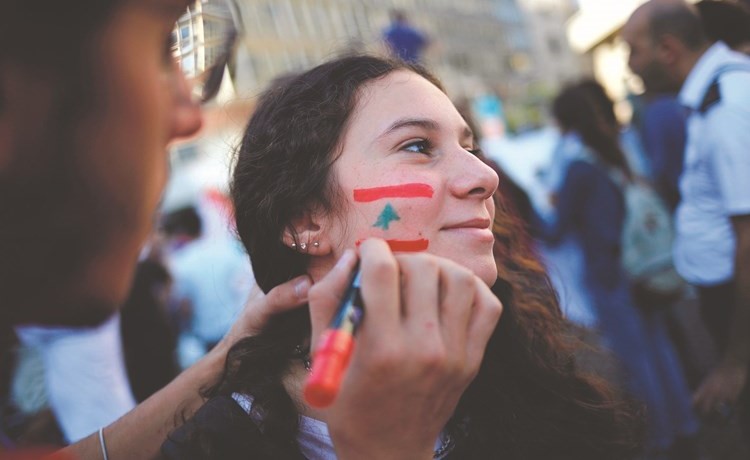 متظاهرة ترسم علم لبنان على وجهها 	(رويترز)﻿