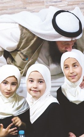 نصار العبدالجليل يطبع قبلة على رأس إحدى أطفال سورية ﻿