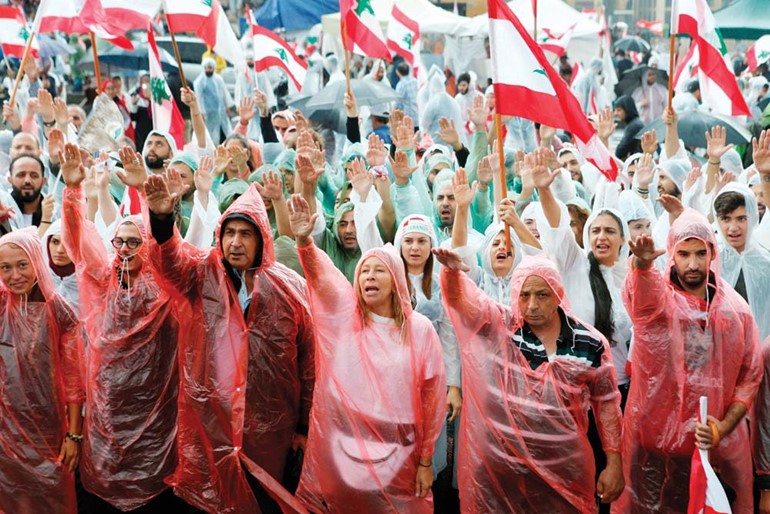 محتجون لبنانيون يتحدون المطر ويتظاهرون في وسط بيروت عقب خطاب الرئيس ميشال عون      (رويترز)