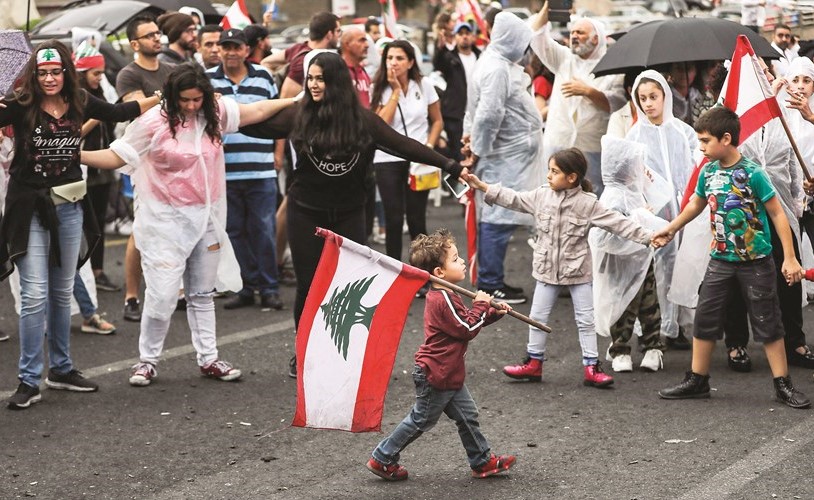 صبي يحمل العلم اللبناني وبجانبه محتجون في زوق مصبح شمال بيروت امس	(أ.ف.پ)﻿