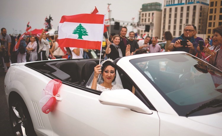 عريس وعروسه يلوحان بالعلم اللبناني خلال احتجاجات اليوم العاشر وسط بيروت	(رويترز) ﻿