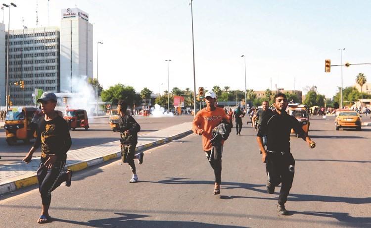 متظاهرون يفرون من قنابل الغاز المسيل للدموع التي اطلقتها قوات الأمن ضدها في بغداد أمس	(رويترز) ﻿