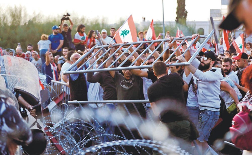 لبنانيون يحاولون إزالة الحواجز التي وضعتها القوات الأمنية لمنعهم من الوصول إلى القصر الرئاسي في بعبدا   	              (أ.ف.پ)