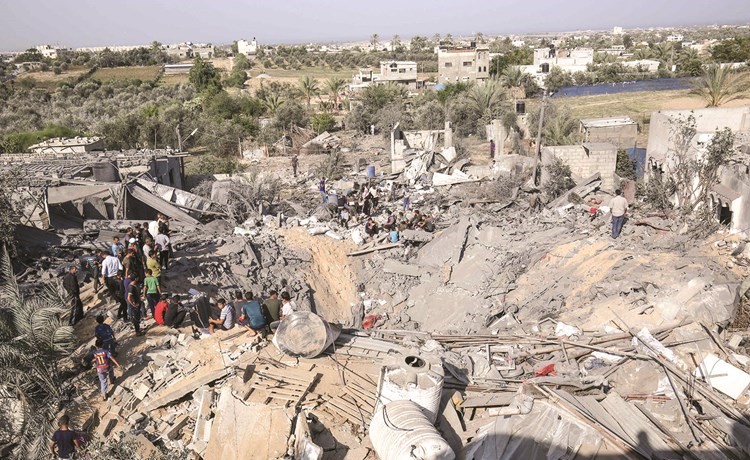 فلسطينيون يتفقدون آثار الدمار الذي خلفته الغارات الاسرائيلية على المباني السكنية بخان يونس في غزة امس	(ا.ف.پ) ﻿