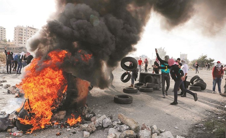 محتجون فلسطينيون يحرقون الإطارات خلال مظاهرة مناهضة لإسرائيل بالضفة الغربية	(أ.ف.پ)﻿