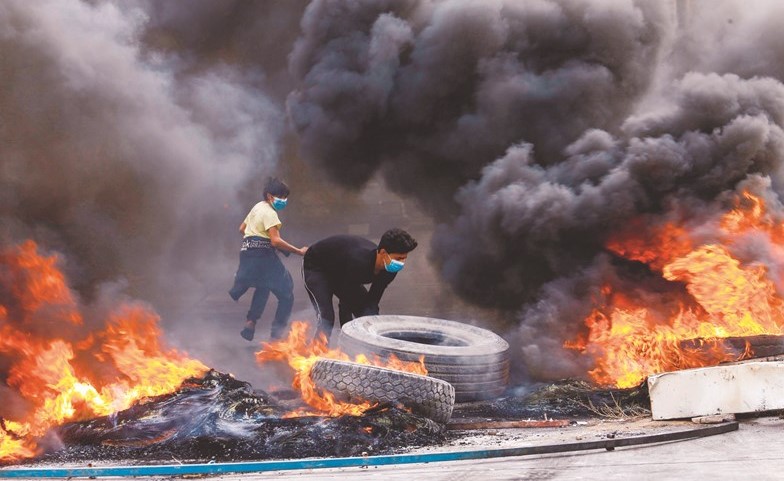 متظاهرون يحرقون إطارات خلال المظاهرات المناهضة للحكومة في النجف	(رويترز)﻿