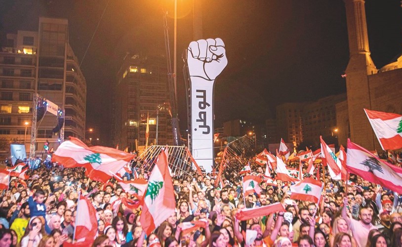متظاهرون يحيطون بمجسم قبضة الثورة الجديد بعد إعادة نصبه في ساحة الشهداء في وسط بيروت﻿
