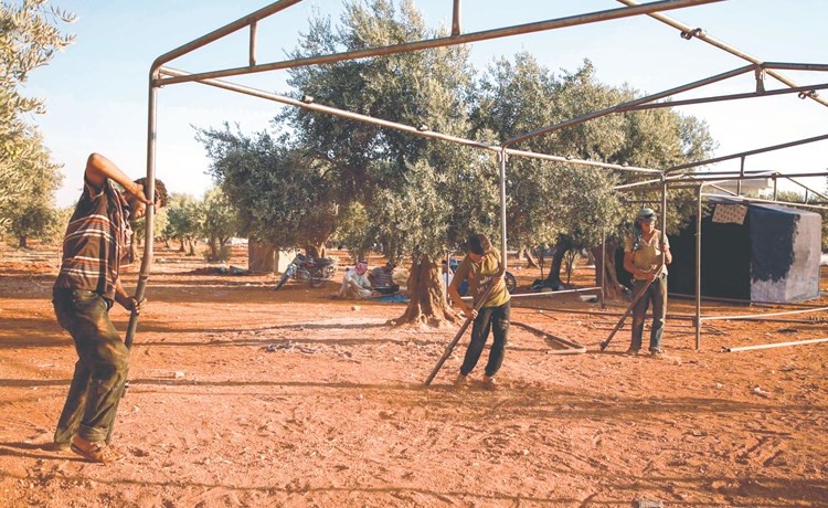 عمال ينصبون القضبان لبناء خيام للنازحين الجدد في بلدة حزانو شمال غرب ادلب	(ا.ف.پ) ﻿