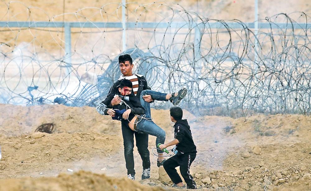 طفل فلسطيني يجلي صديقه المصاب خلال مظاهرة مناهضة للاحتلال في غزة   		   (رويترز)
