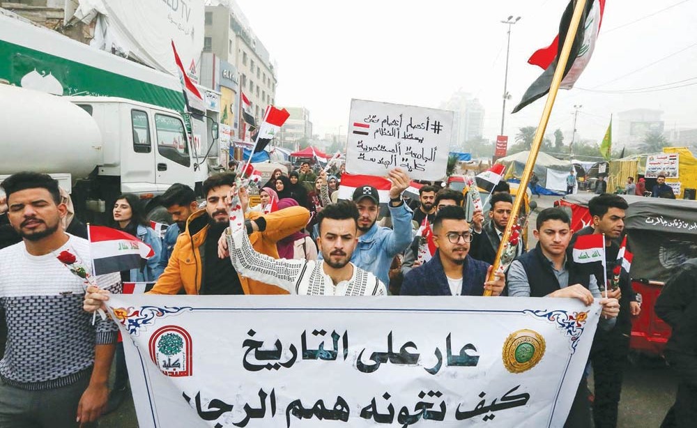 محتجون عراقيون يرفعون لافتات تصر على «اسقاط النظام» في ساحة التحرير وسط بغداد           (أ.ف.پ)