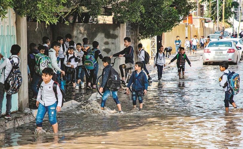 تلاميذ اثناء عودتهم إلى منازلهم في أحد الشوارع التي غمرتها الفيضانات في البصرة	(أ.ف.پ)