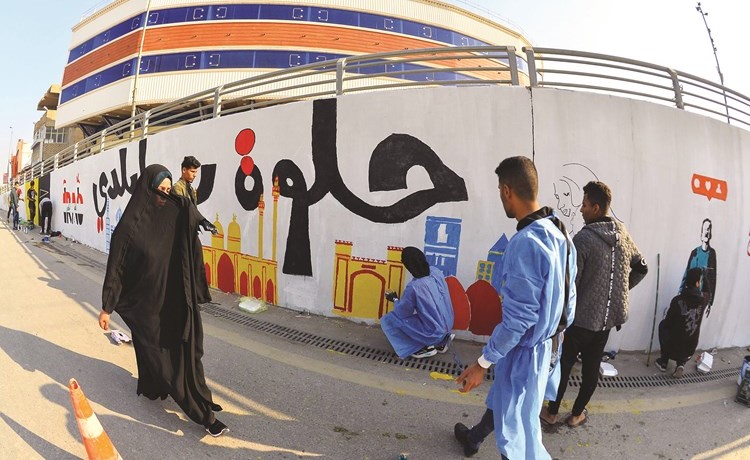رسامو الاحتجاجات في العراق يضعون اللمسات الاخيرة على غرافيتي باحد حوائط شوارع النجف أمس	(ا.ف.پ)
