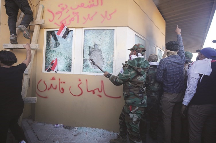 محتجون عراقيون بينهم عناصر من الحشد الشعبي خلال محاولة اقتحام السفارة الأميركية أمس	(أ.ف.پ)