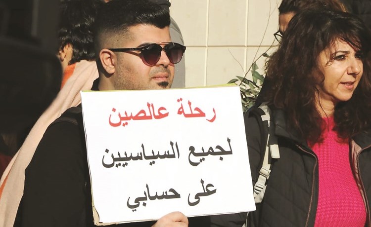 متظاهر يحمل لافتة تطالب بـ رحلة عالصين لجميع السياسيين على حسابي خلال مسيرةللحراك الشعبي أمس	(محمود الطويل)