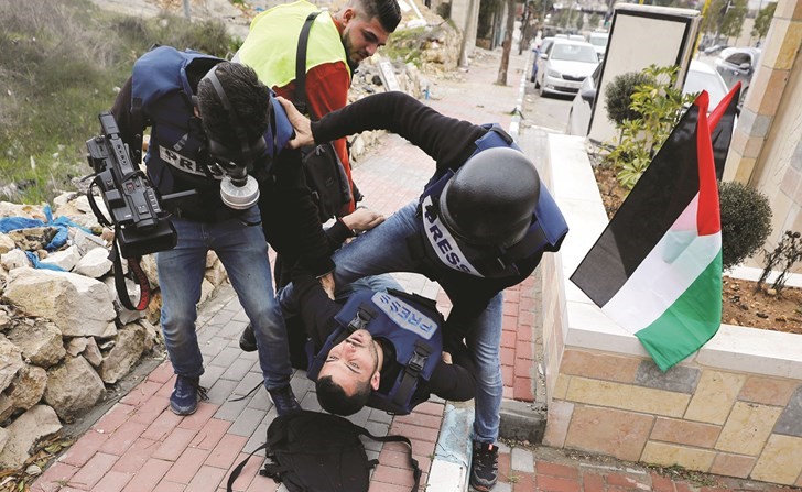 مصورون صحافيون فلسطينيون يحاولون اسعاف زميل لهم اصيب خلال مواجهات مع قوات الاحتلال في الخليل بالضفة امس	(رويترز)