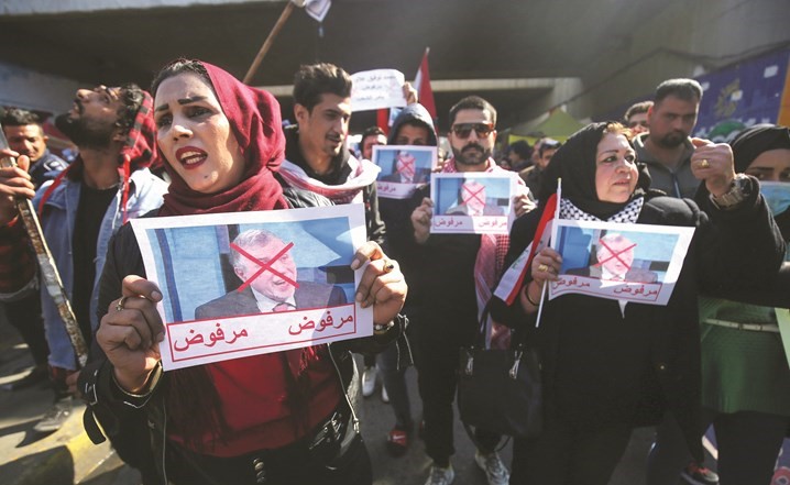 عراقيون يرفعون صورا مشطوبا عليها لرئيس الوزراء المكلف خلال احتجاجات رافضة له ببغداد امس	(ا.ف.پ)
