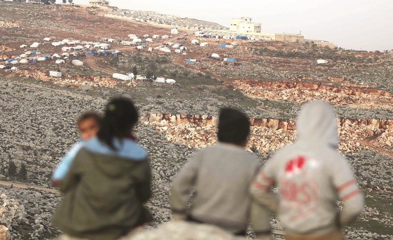 أطفال نازحون يراقبون مخيما مؤقتا اقيم في ريف إدلب	(أ.ف.پ)