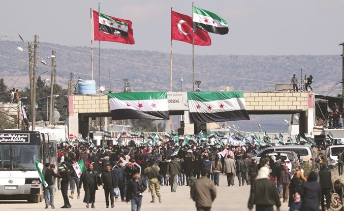 نازحون سوريون يرفعون علم المعارضة في مسيرة قرب معبر باب السلام لدعم العمليات العسكرية التركية وفصائل المعارضة في ادلب(رويترز)