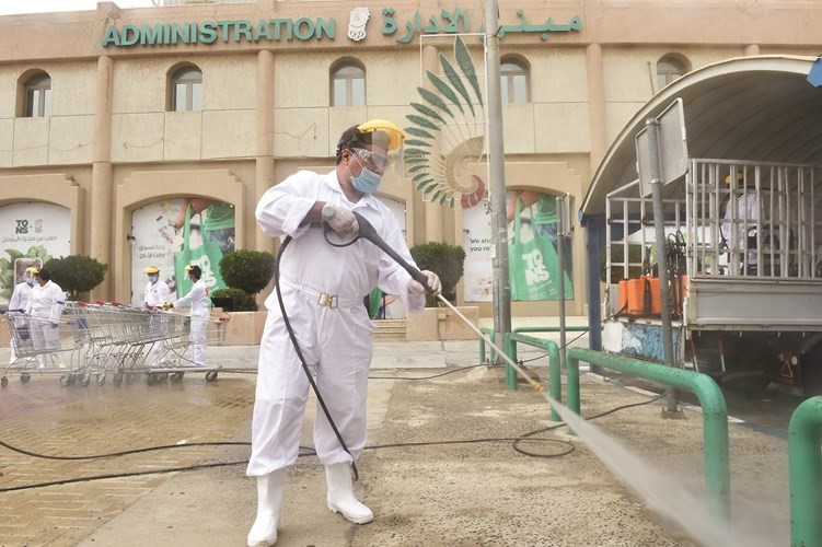 أحد الشباب المتطوعين خلال تعقيم مدخل الجمعية