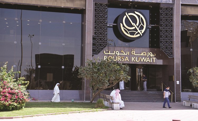 متداولون يقفون خارج مبنى بورصة الكويت أمس في محاولة لمتابعة عمليات التداول بالسوق(قاسم باشا)