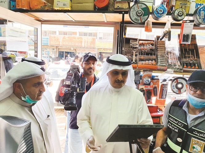 م.أحمد المنفوحي وفيصل الجمعة خلال التدقيق على تراخيص أحد المحلات