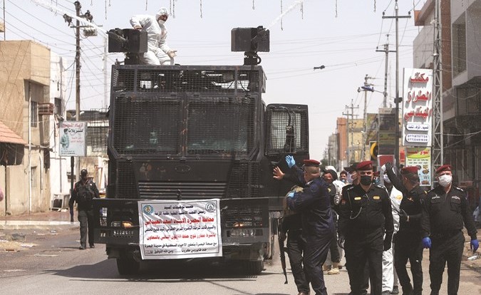 قوات مكافحة الشغب العراقية خلال تعقيمها شوارع البصرة ضد ڤيروس كورونا أمس	(رويترز)