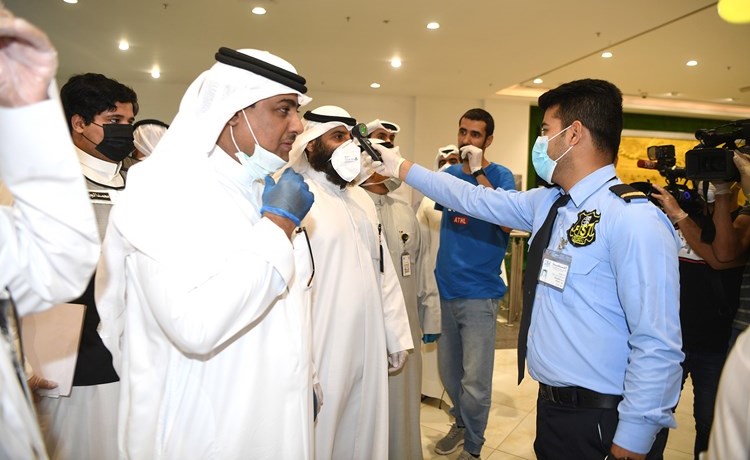 قياس درجة حرارة فريق البلدية قبيل دخول محل تجاري