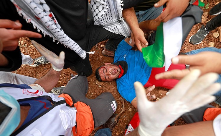 فلسطينيون يسعفون احد المصابين سقط خلال اعتداءات قوات الاحتلال على محتجين في ذكرى النكبة	(رويترز)