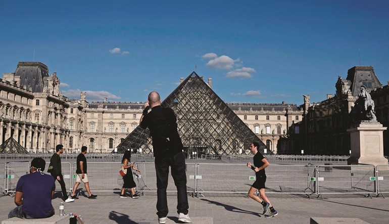 باريسيون يتريضون أمام هرم اللوڤرفي ساحة نابليون بباريس بعد تخفيف الاجراءات(أ.ف.پ)