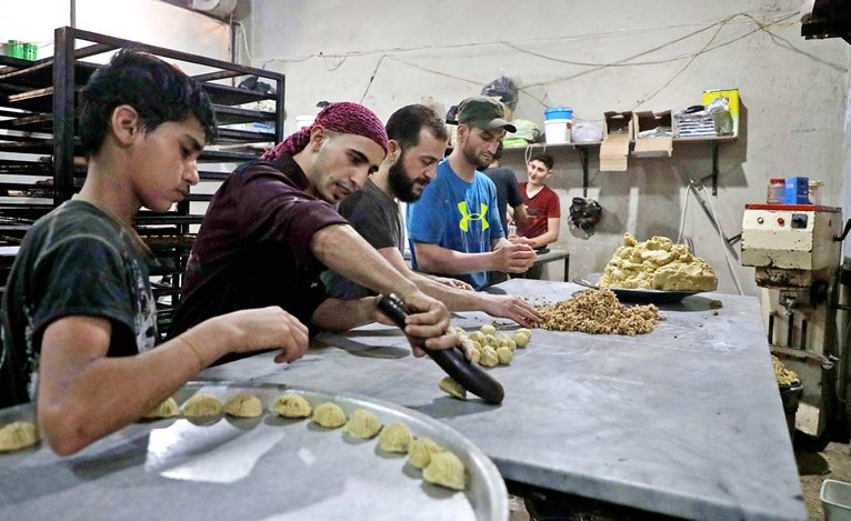 سوريون يحضرون حلويات العيد في مخبز يديره نازحون في بلدة الدانة بريف ادلب	(ا.ف.پ)
