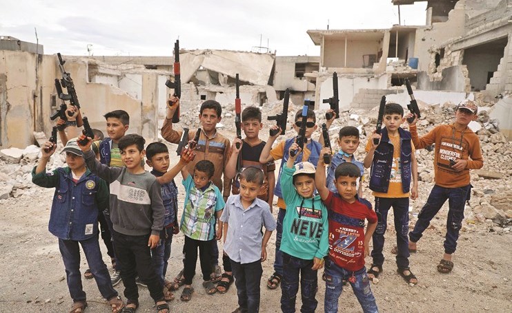 أطفال سوريون يلتقطون صورة بالبنادق البلاستيكية بأول أيام العيد في الريف الغربي لحلب الشمالية (أ.ف.پ)