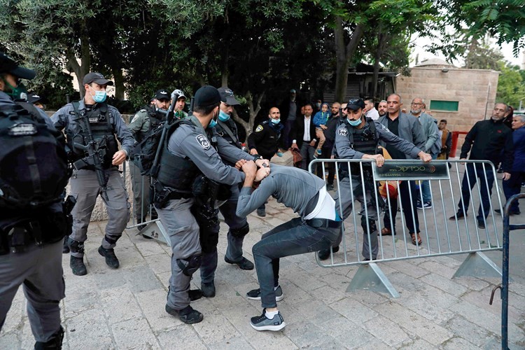 قوات الاحتلال تعتدي على فلسطيني قرب المسجد الأقصى وفي الكادر فلسطينيون يقيمون صلاة عيد الفطر في احد الملاعب بالضفة المحتلة(أ.ف.پ)