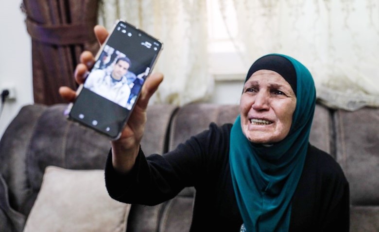 والدة الشهيد اياد الحلاق تبكي وتحمل صورته في الهاتف	(أ.ف.پ)