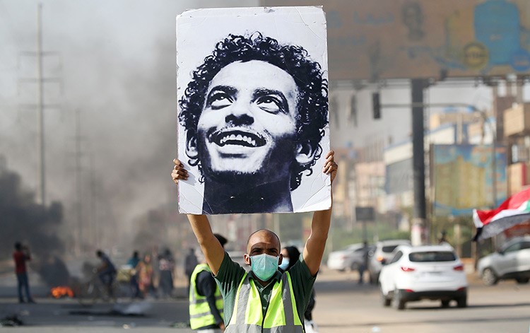 متظاهر يرفع صورة أحد شهداء فض اعتصام مقر قيادة الجيش خلال احتجاجات في الذكرى الاولى بالخرطوم (ا.ف.ب)