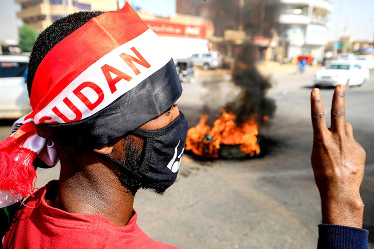 متظاهر يرفع إشارة النصر خلال احتجاجات بالخرطوم في الذكرى الاولى لفض اعتصام مقر قيادة الجيش (ا.ف.ب)