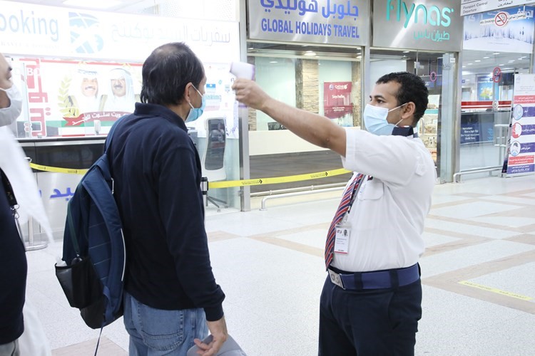 قياس درجة حرارة أحد المسافرين قبل دخول الصالة