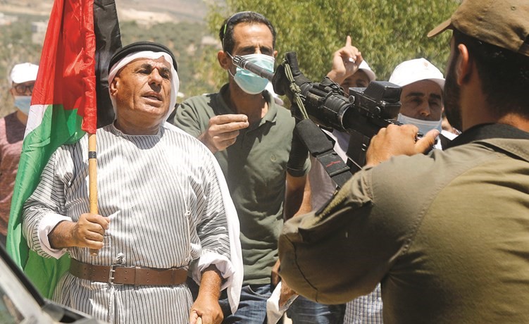 فلسطينيون يواجهون جنديا إسرائيليا مسلحا خلال تظاهرة في نابلس امس احتجاجا على خطط ضم الضفة	(رويترز)