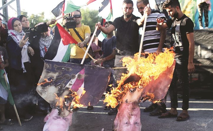 فلسطينيون يحرقون صور الرئيس الاميركي دونالد ترامب ورئيس الوزراء الاسرائيلي بنيامين نتنياهو خلال احتجاجات مناهضة للضم في غزة امس(رويترز)